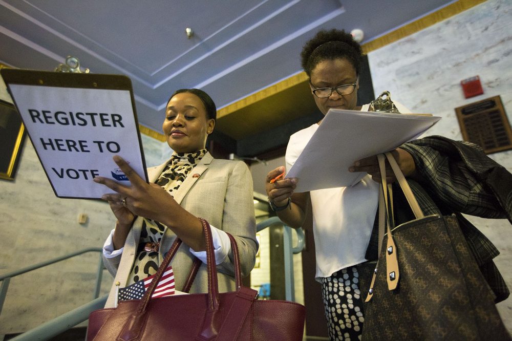 Emmy Shange from Tanzania (left) and Sandra Lebrun from Haiti register to vote immediately after the naturalization ceremony. (Jesse Costa/WBUR)