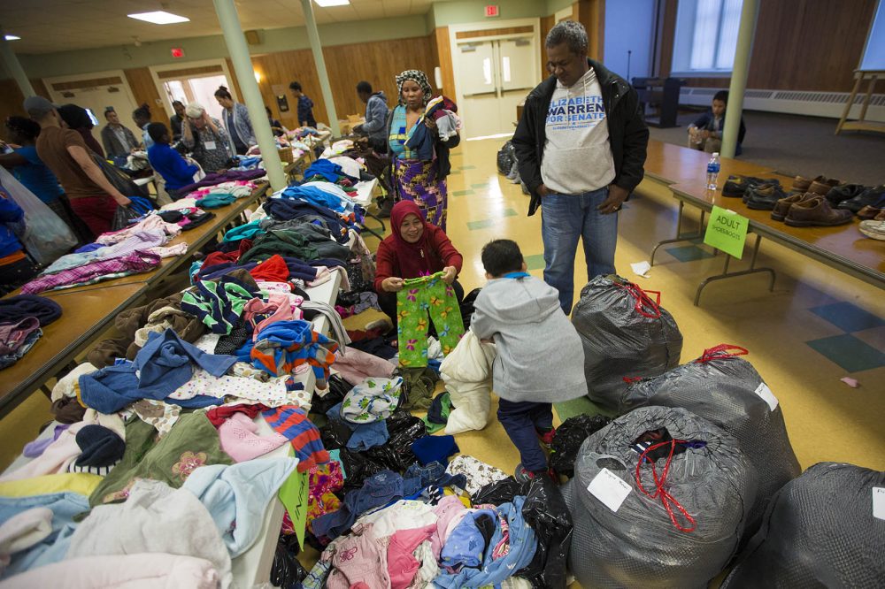 Families fill plastic bags from the clothing drive in Lowell. (Jesse Costa/WBUR)