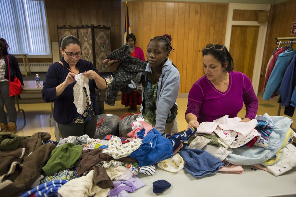 Refugees relocated to the Lowell area look through clothing for something warm. (Jesse Costa/WBUR)