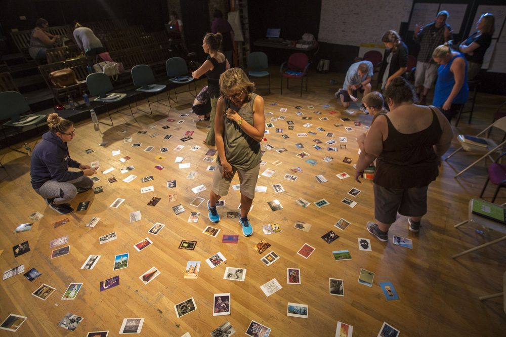 Teachers peruse an assortment of postcards on the floor. (Jesse Costa/WBUR)