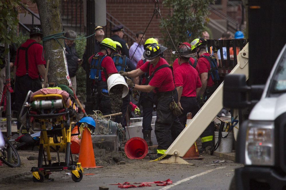Workers clear out a trench that flooded from a water main break. (Jesse Costa/WBUR)