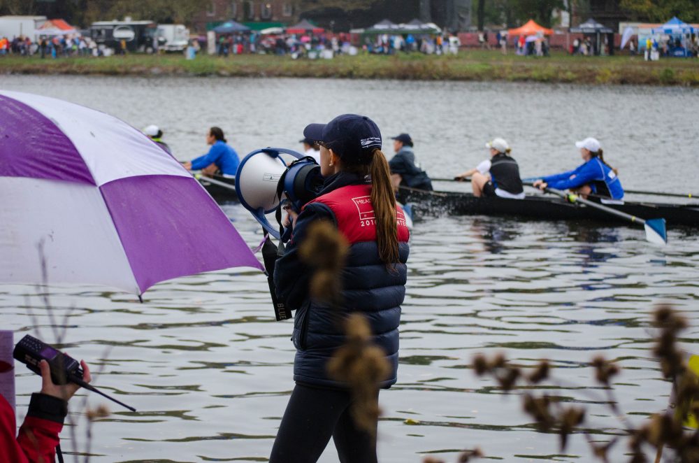 Michaela Rosmarin directs boats under the Weeks Footbridge near Harvard University. Rosmarin and her twin sister, Nicole, have been volunteering as river patrol at the Head of the Charles for four years. (Elizabeth Gillis/WBUR)