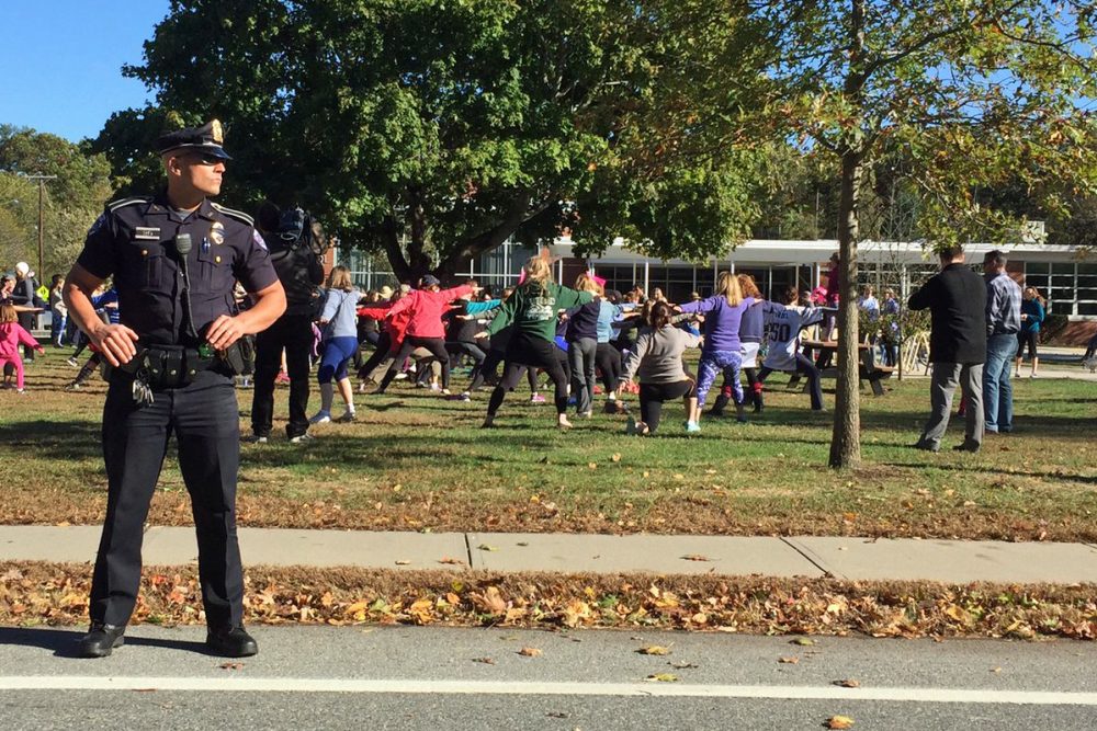Parade attendees do yoga as a police officer looks on during a parade in support of wearing yoga pants Sunday in Barrington, R.I. (Courtesy Selena Maranjian)