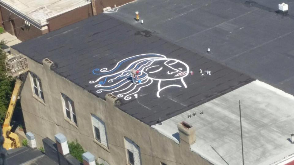 An artist works on a rooftop art installation in Jefferson, Iowa. (Courtesy Jefferson Matters: Main Street)