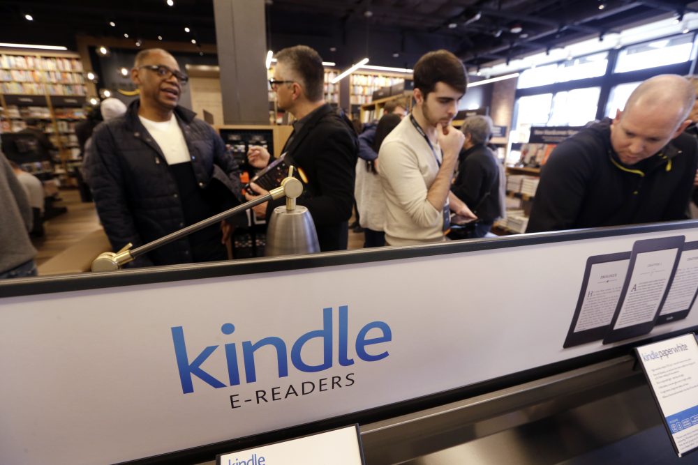 Customers stand near a display of Kindle electronic readers at the opening day for Amazon Books, the first brick-and-mortar retail store for online retail giant Amazon, Nov. 3, 2015, in Seattle. (Elaine Thompson/AP)