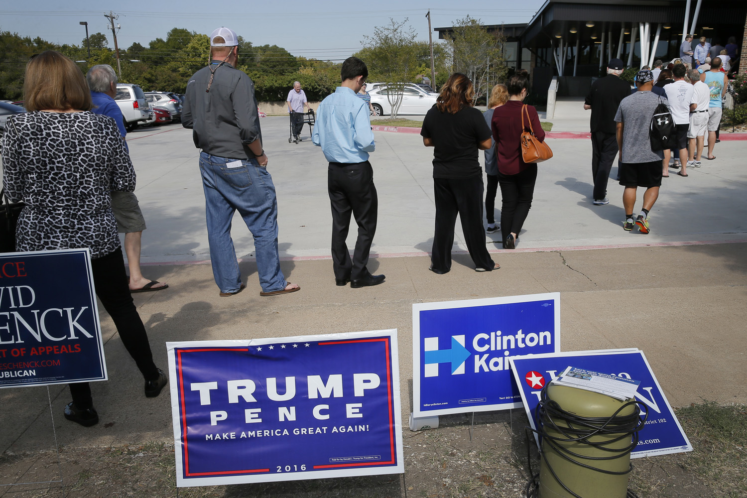 Early voters stand by campaign signage as they wait in line at a voting location in Dallas. (Tony Gutierrez/AP)