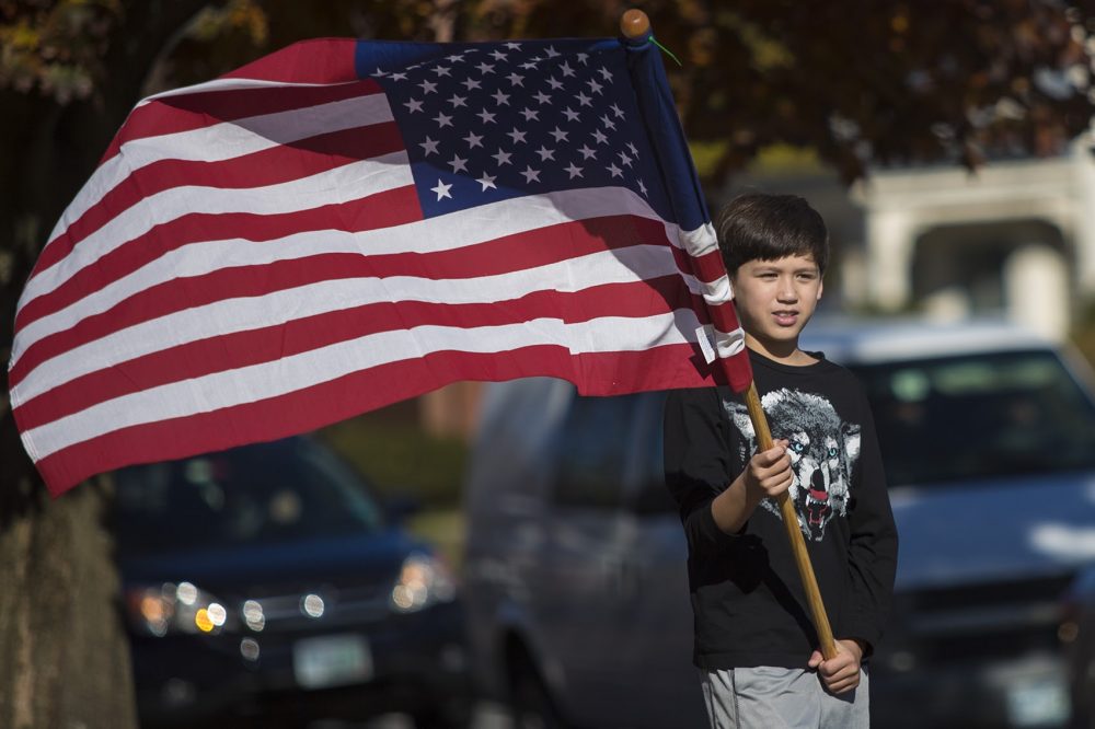 Christopher Cheung, of Braintree, holds an American flag in Nashua, N.H. while helping his mom campaign for Donald Trump. (Jesse Costa/WBUR)