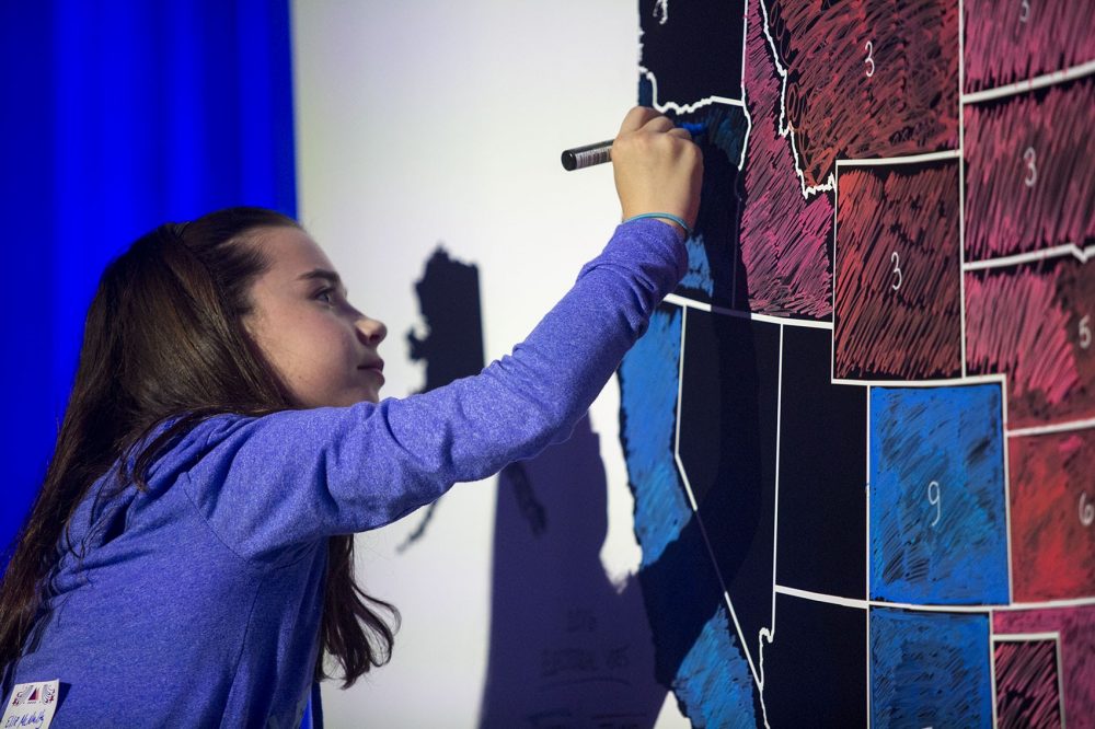 Ellie McNulty, who says she'll be in the future Class of 2028, colors in Oregon after it's announced that Clinton took the state. (Jesse Costa/WBUR)