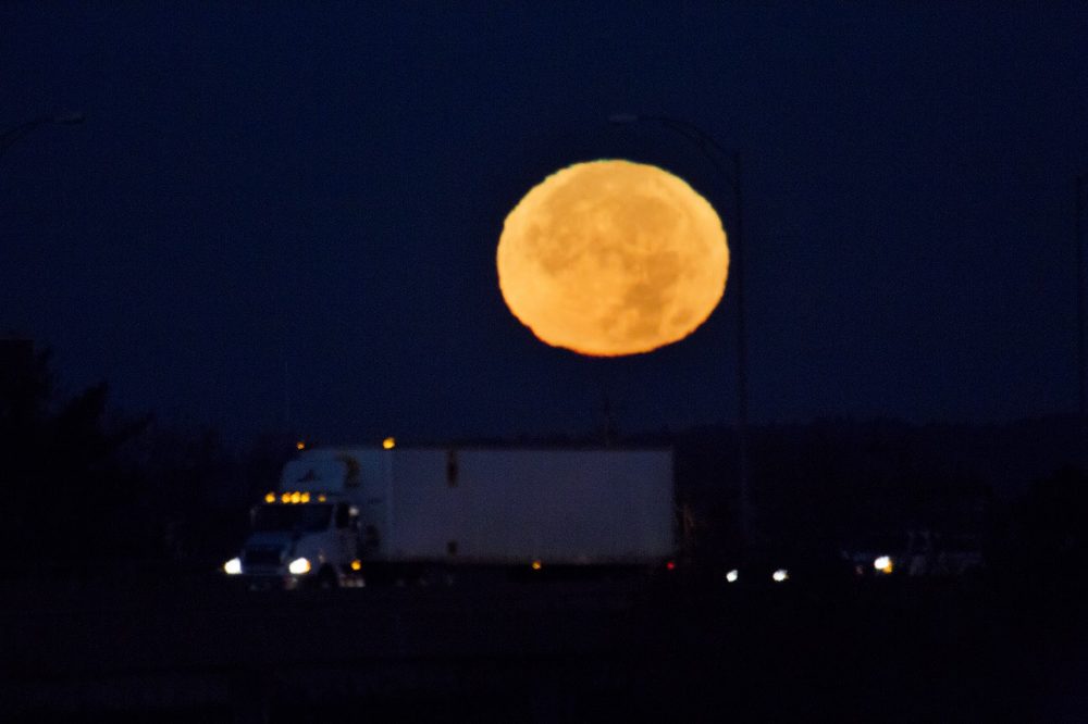 The supermoon sets behind the Mass. Pike at 6:09 a.m. on Monday. (Jesse Costa/WBUR)