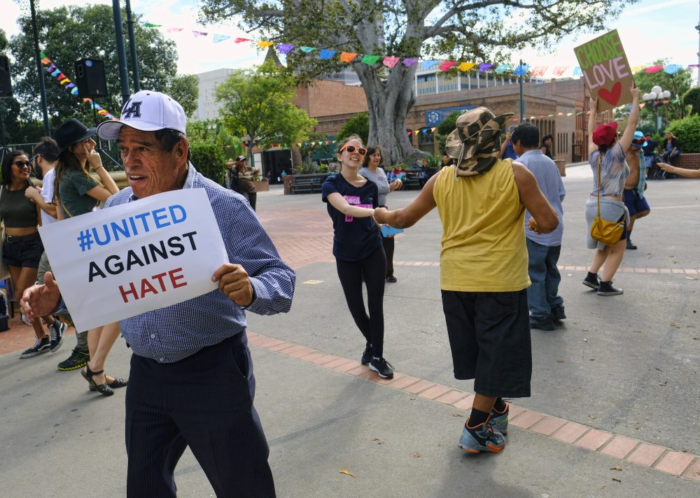 A man carrying a sign that reads "United Against Hate" dances with other demonstrators during a demonstration against presidential elect Donald Trump in Oliveira Plaza in downtown Los Angeles on Saturday, Nov. 12, 2016. (Richard Vogel/AP)