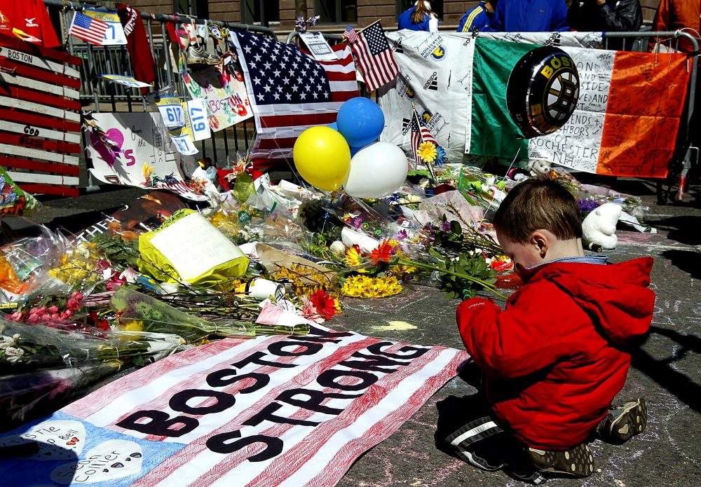 Two-year-old Wesley Brillant of Natick kneels in front of a memorial to the victims of the Boston Marathon bombings near the scene of the blasts on Boylston Street. (Courtesy Jim Reuters/HBO)