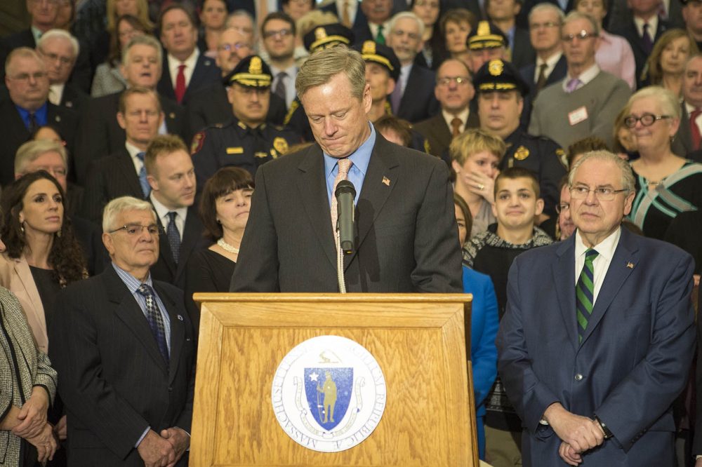 Surrounded by lawmakers and health and public safety officials, Gov. Charlie Baker signs the opioid bill into law at the State House. (Jesse Costa/WBUR)