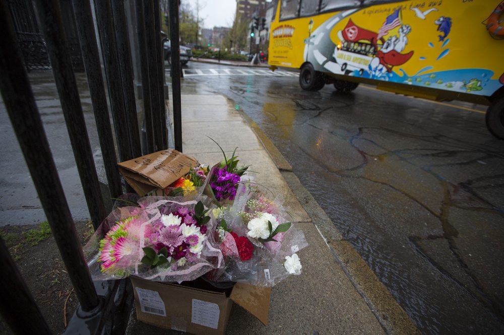 A duck boat tour bus passes by a memorial for Allison Warmuth in the rain on the corner of Charles and Beacon Streets. (Jesse Costa/WBUR)