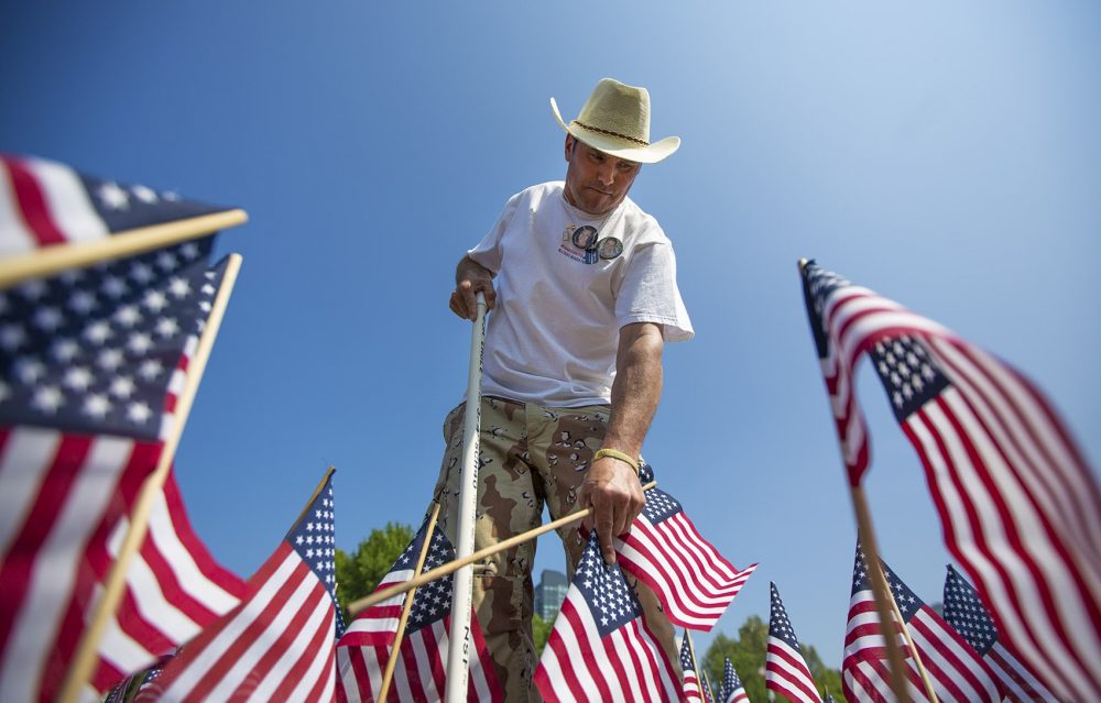 Carlos Arredondo plants flags for the Massachusetts Heroes Fund flag garden for Memorial Day. (Jesse Costa/WBUR)