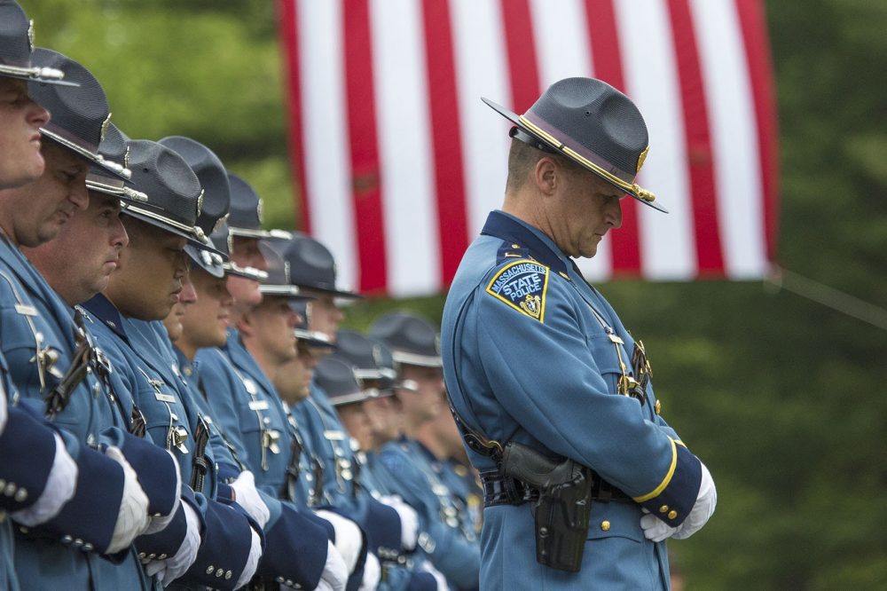 A Mass state trooper hangs his head during Ronald Tarentino's funeral in Charlton. Tarentino, an Auburn police officer, was shot and killed during a traffic stop. Hundreds of police officers stood outside the church during his service to honor him (Jesse Costa/WBUR)