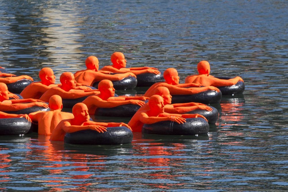 Ann Hirsch and Jeremy Angier's “SOS (Safety Orange Swimmers)” floating in Boston's Fort Point Channel. (Jesse Costa/WBUR)
