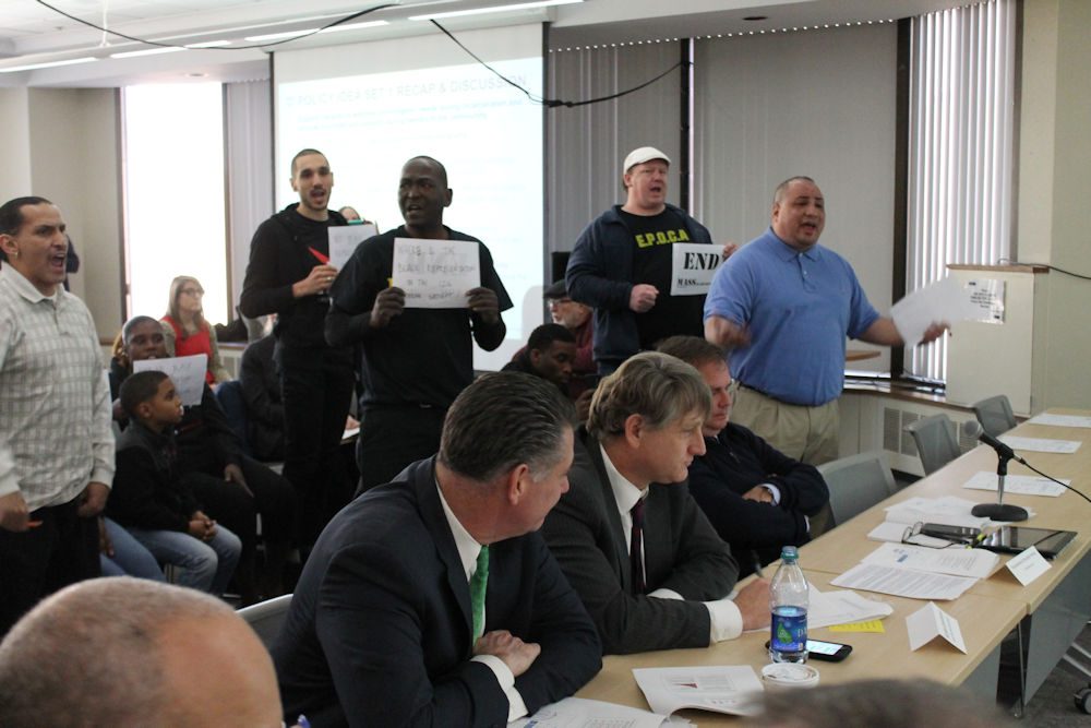Calvin Feliciano (far right), deputy political director for SEIU 509, interrupted Wednesday's meeting of a criminal justice working group to express the need for sentencing reforms and led protesters in a &quot;Jobs not Jails&quot; chant. (Antonio Caban/SHNS)
