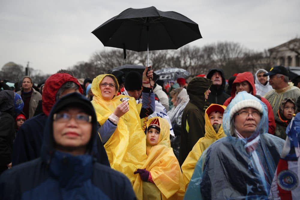 Spectators wait in the rain on the National Mall in Washington before the inauguration ceremony. (John Minchillo/AP)