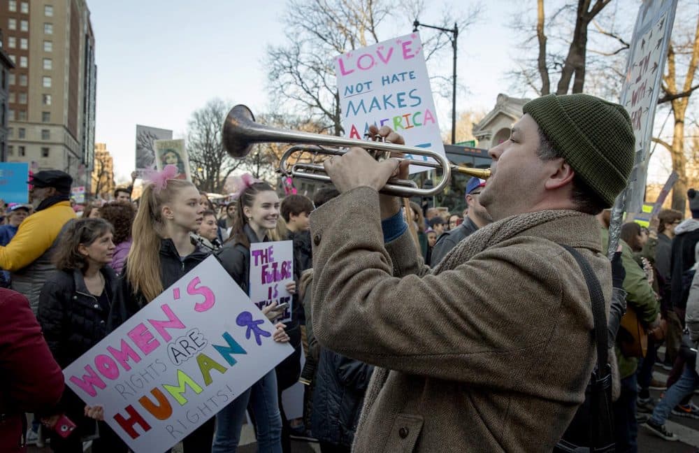 Jason McCool plays &quot;We Shall Overcome&quot; on his trumpet as marchers walk by the Boston Public Garden. (Robin Lubbock/WBUR)