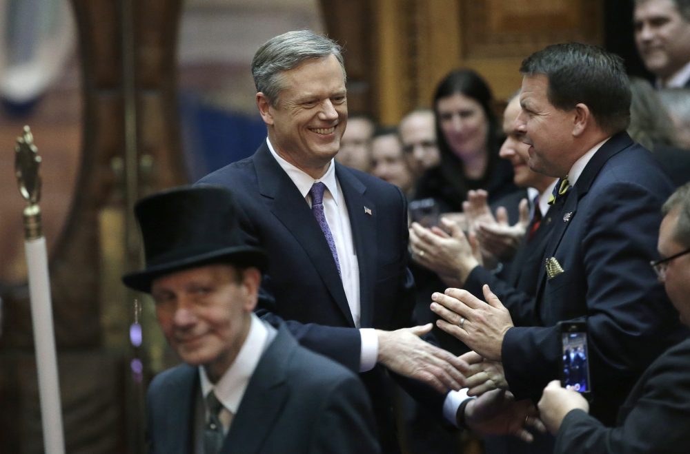 Baker greets lawmakers and guests as he enters the House chamber led by the Sergeant-at-Arms of the House Raymond Amaru, front left, before his State of the State address. (Steven Senne/AP)