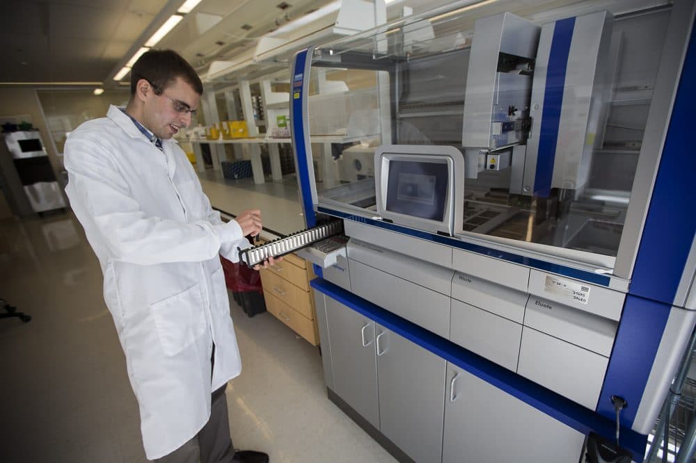 Viktor Adalsteinsson, leader of the Blood Biopsy Group at the Broad Institute, inserts a tube into a robotic system that extracts tumor and normal DNA fragments from blood. (Jesse Costa/WBUR)