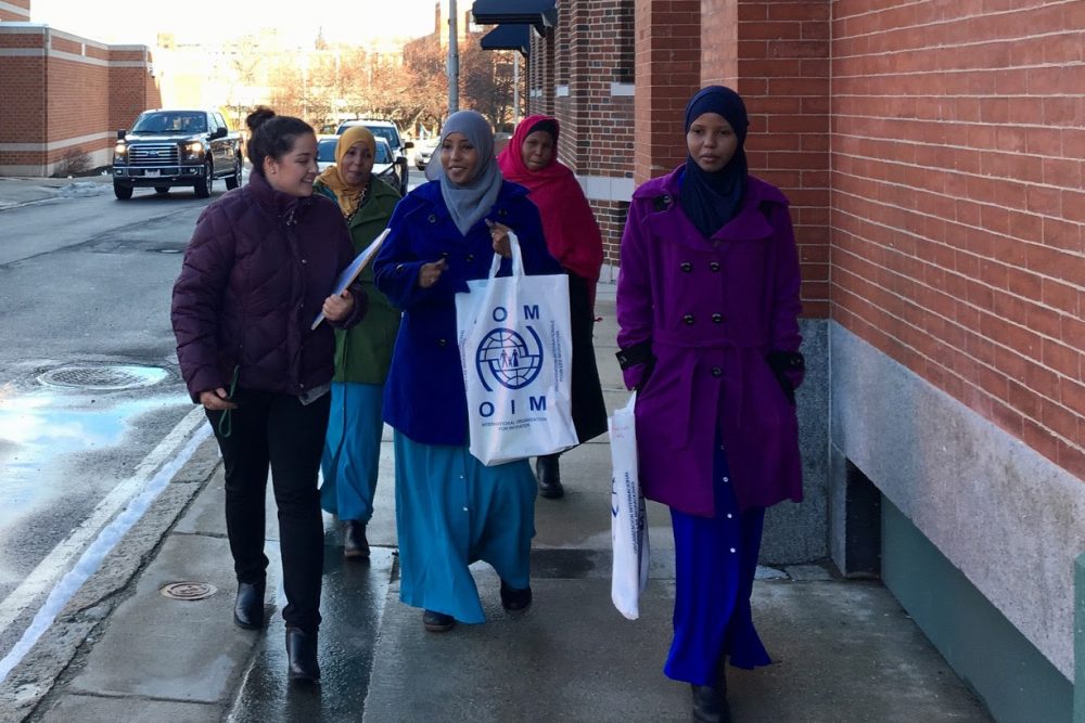 A volunteer from the International Institute of New England, far left, helps the Ahmed family get to the Department of Transitional Assistance's Lowell office. (Shannon Dooling/WBUR)