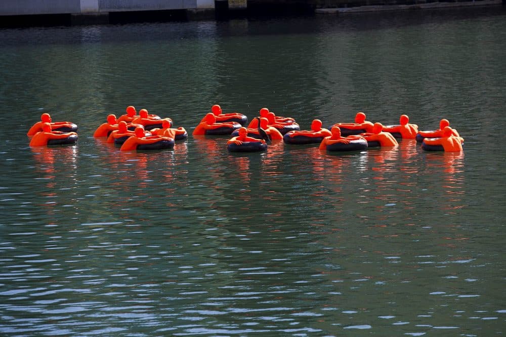 The floating art piece called SOS (Safety Orange Swimmers) in the Fort Point Channel. (Jesse Costa/WBUR)