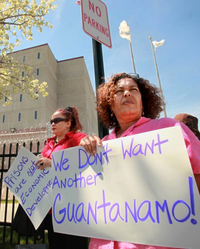 Protesters display signs outside the Wyatt Detention Facility on April 28, 2009, where they gathered to urge federal officials against returning immigration detainees to the quasi-public prison. Hiu Lui Ng, a Chinese immigrant, died of cancer at the facility in 2008. (Steven Senne/AP)