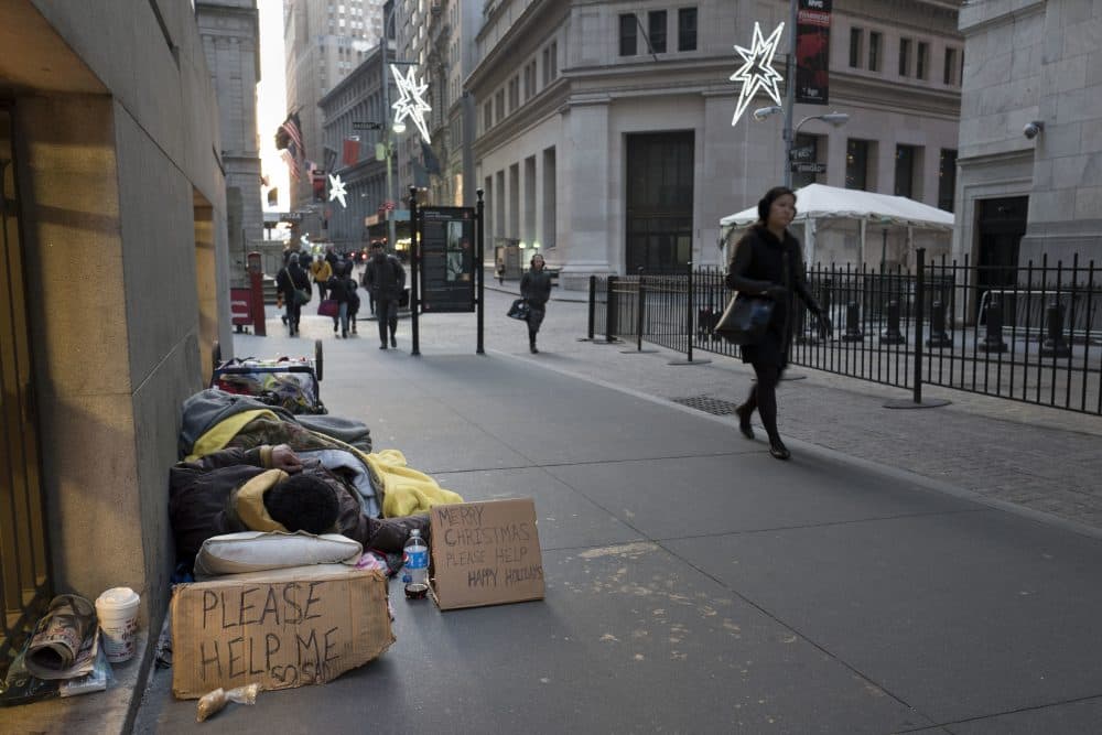 A homeless man sleeps on Wall Street near the New York Stock Exchange, Wednesday, Dec. 21, 2016. (Mark Lennihan/AP)