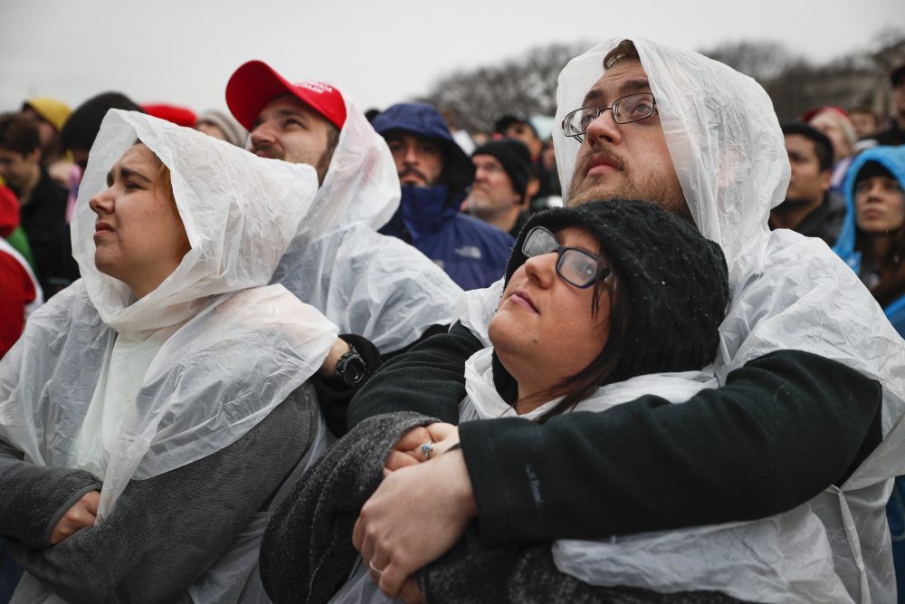Spectators embrace as President-elect Donald Trump speaks during his inauguration. (John Minchillo/AP)