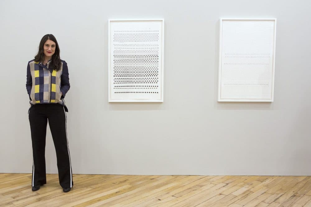 Artist Carly Glovinski stands next to her works &quot;DARKERearlier,&quot; left, and &quot;LIGHTERlater&quot; on display at the Carroll and Sons gallery in the South End. (Jesse Costa/WBUR)