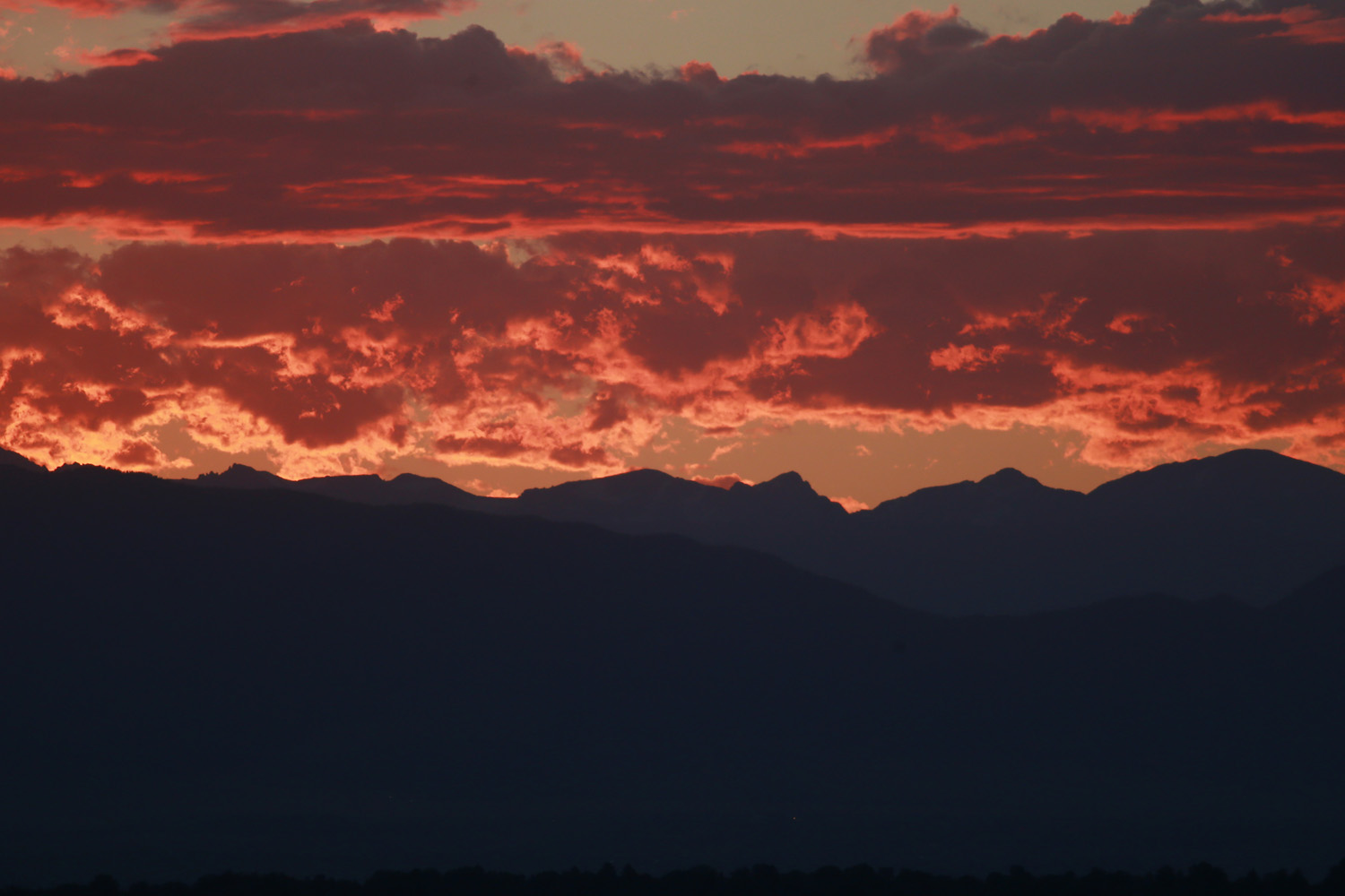 In this file photo, the sun sets behind the Rocky Mountains and a golden light illuminates the clouds late in Denver. (David Zalubowski/AP)