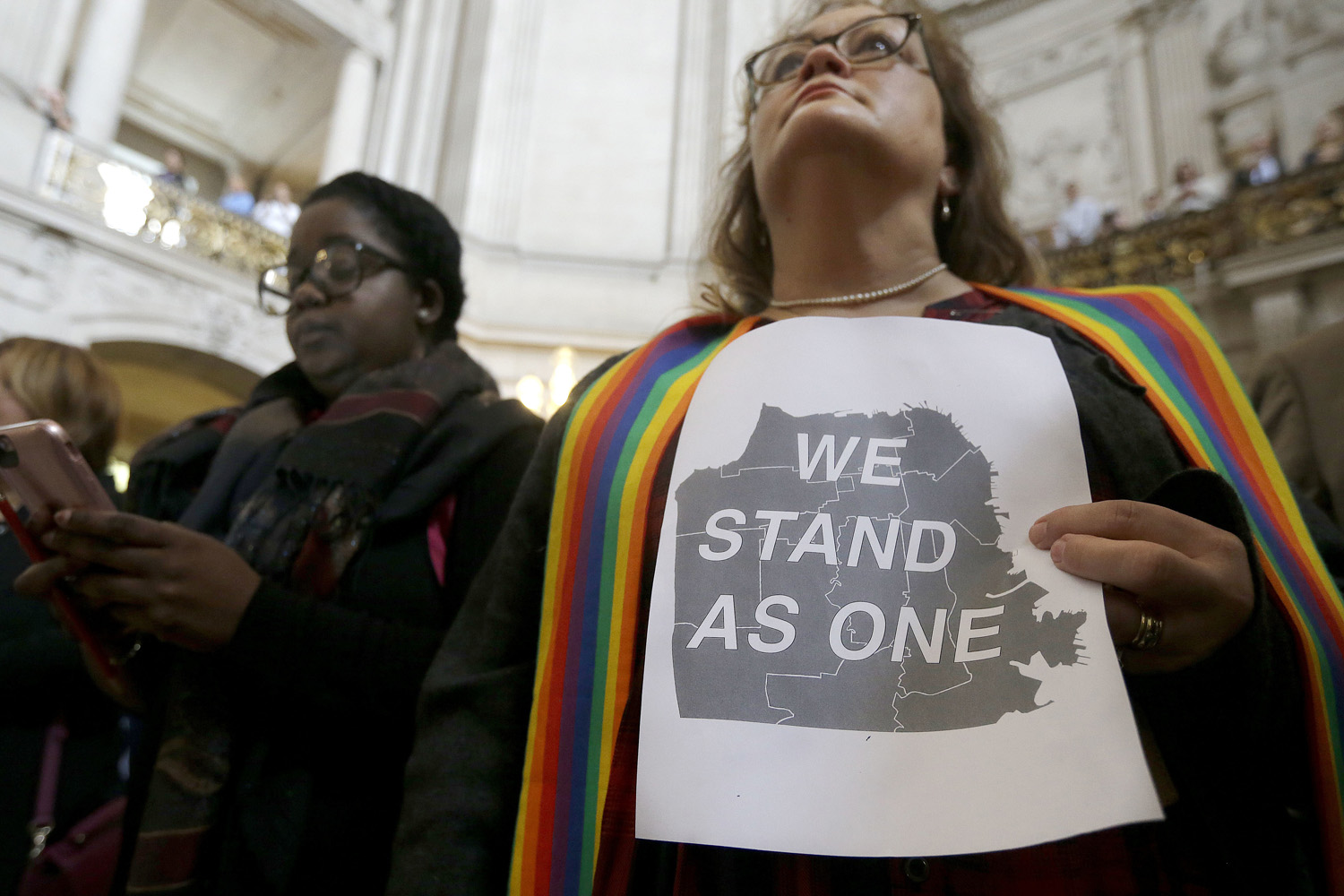 In this file photo, The Rev. Annie Steinberg-Behrman, right, provisional pastor with Metropolitan Community Church, holds a sign while listening to speakers at a meeting at City Hall in San Francisco by city leaders and community activists to reaffirm the city's commitment to being a sanctuary city. (Jeff Chiu/AP)