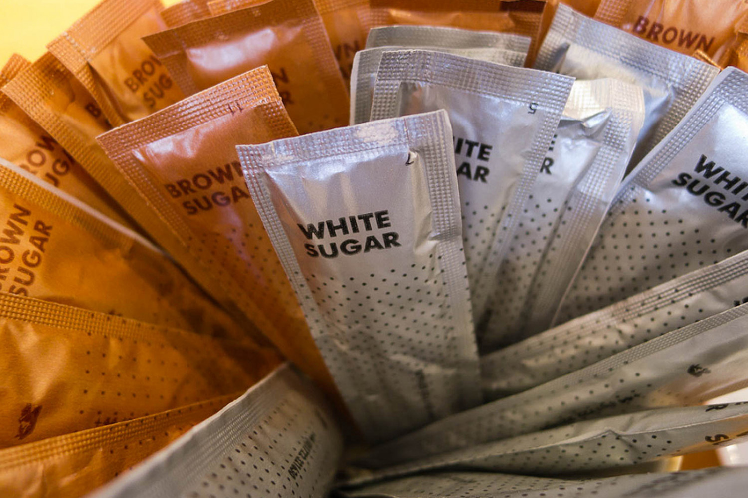 A collection of brown and white sugar packets. (James Brooks/Flickr)