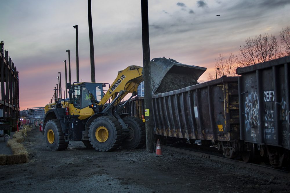 A land mover dumps excavated soil from the Wynn site. (Jesse Costa/WBUR)