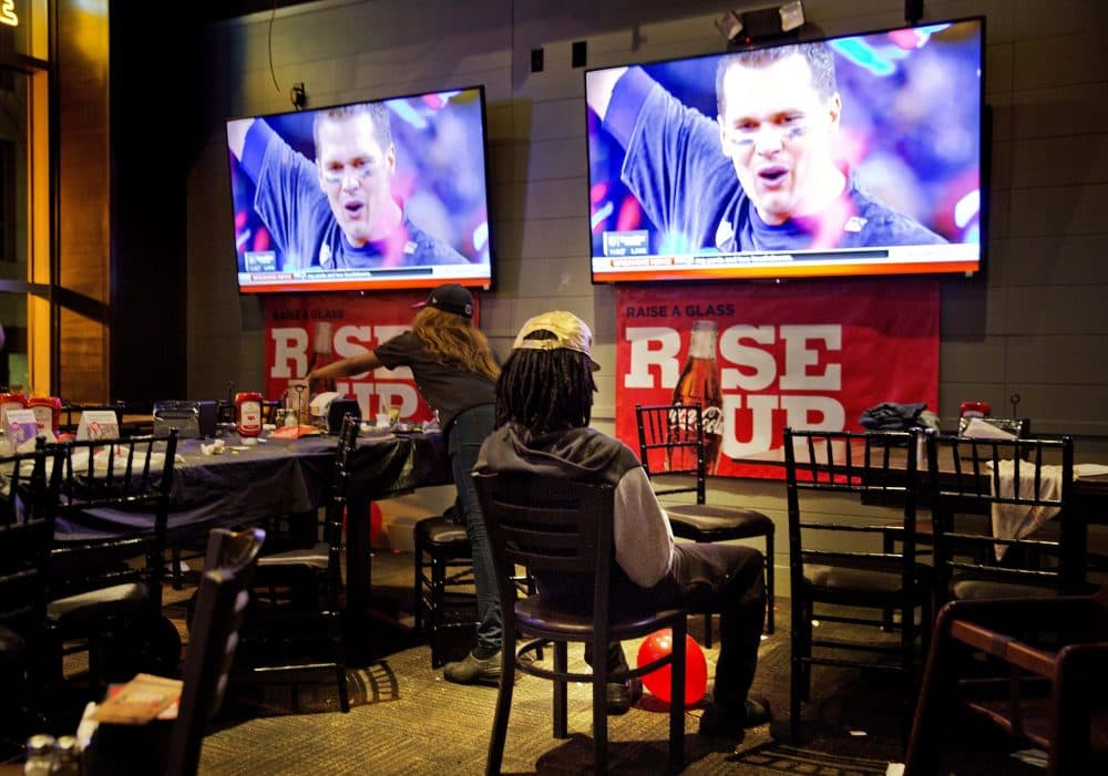 Atlanta Falcons fan Xavier Jackson sits beneath television screens at a restaurant in Atlanta showing New England Patriots quarterback Tom Brady celebrating after the Patriots beat Atlanta in the Super Bowl. (David Goldman/AP)