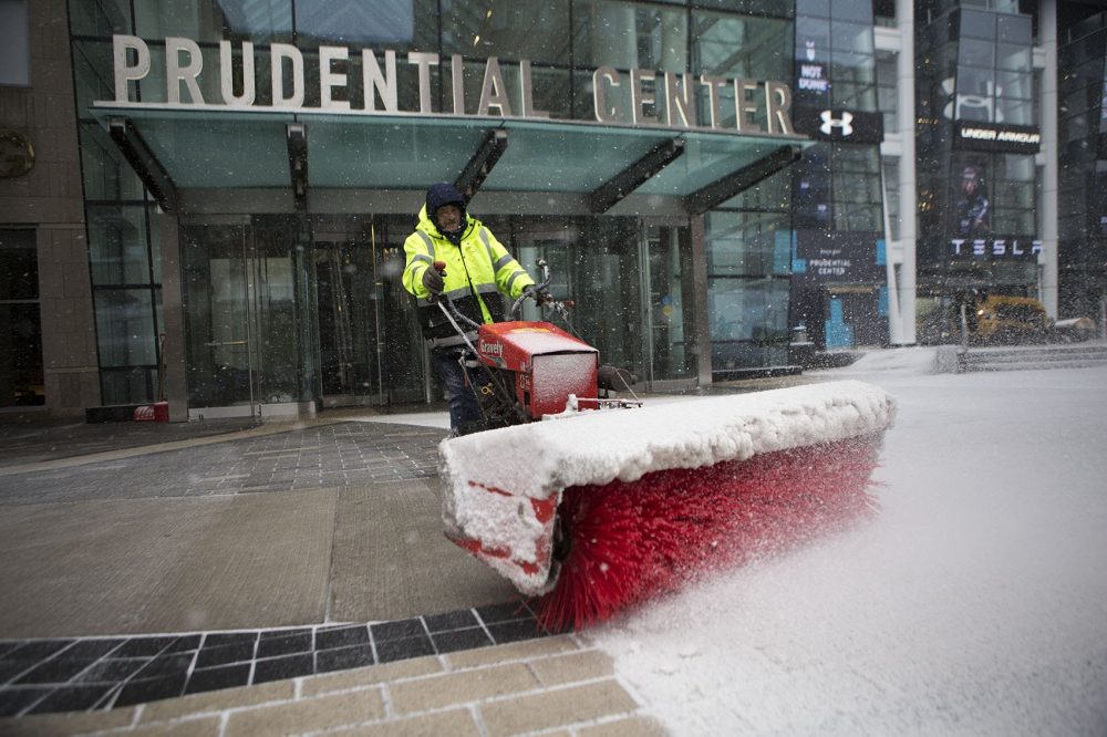 A worker clears snow in front of the Prudential Center with a snow sweeper. (Jesse Costa/WBUR)