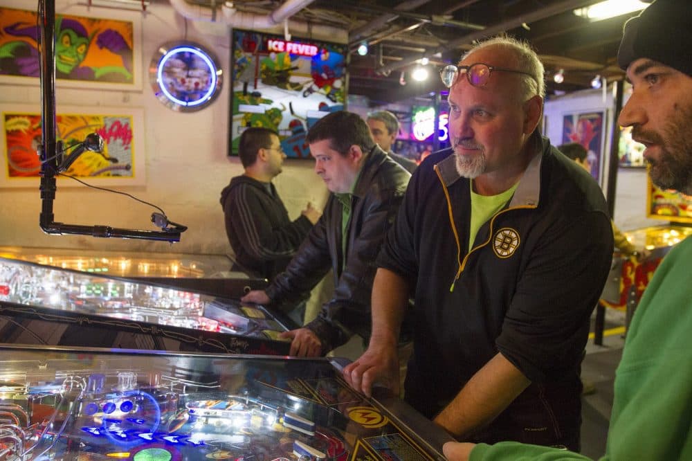 Chuck Webster (with the Bruins shirt) runs The Wicked Pissa Pinball Pit out of his home in Wakefield. (Joe Difazio for WBUR)