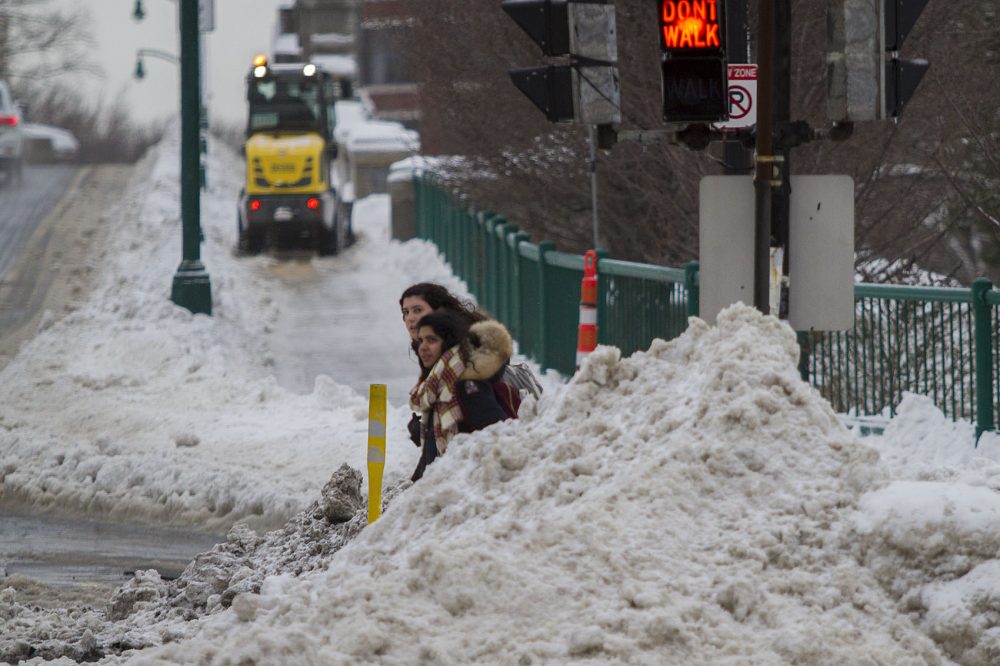 Two Boston University Students peer out from the side of a snow bank as the attempt to cross the BU Bridge road at Commonwealth Ave. (Jesse Costa/WBUR)