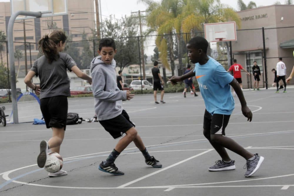 Khalil Aboona (middle) and Sadik Kabera (right) play pick-up soccer. (Erin Siegal McIntyre/KQED)