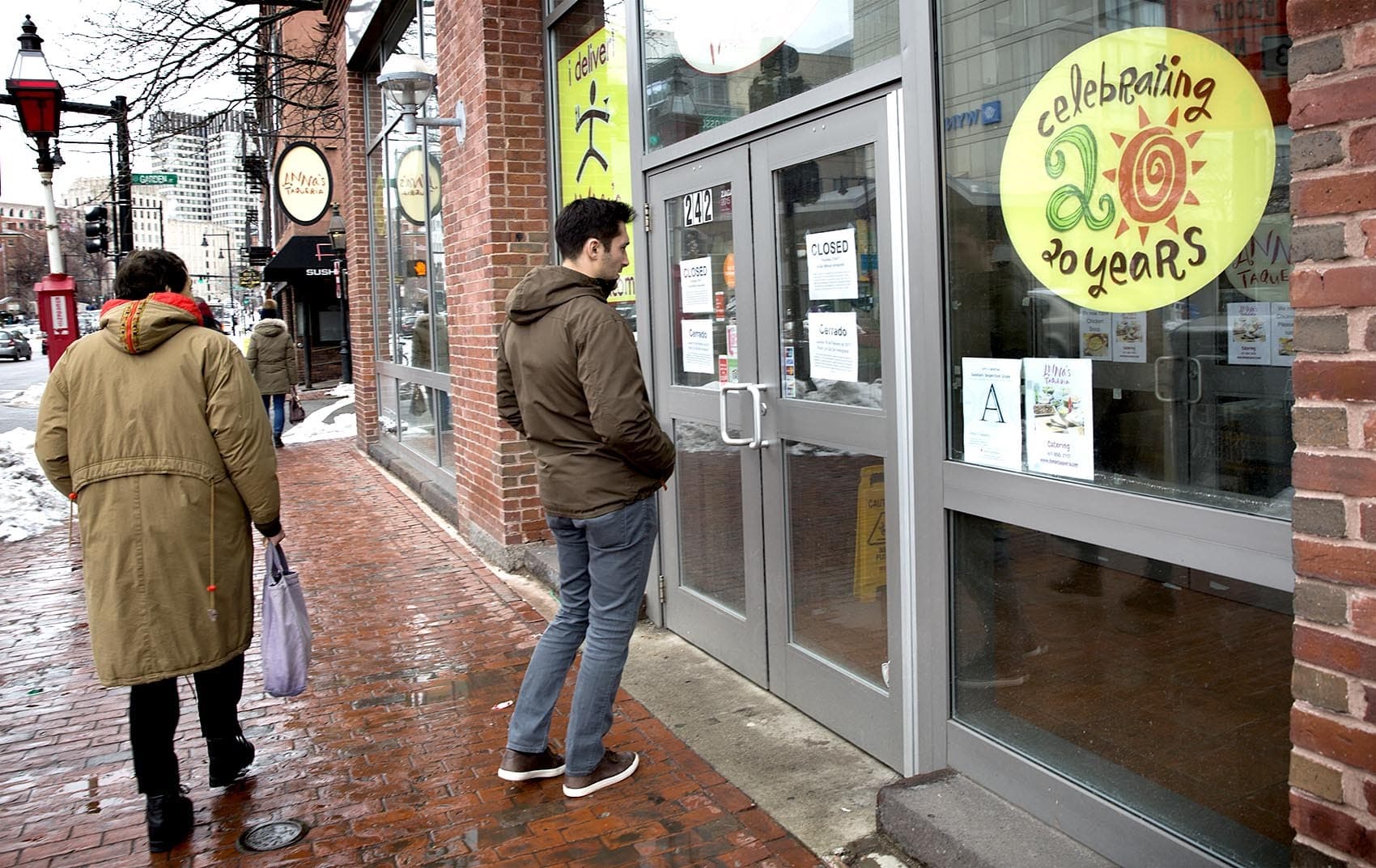 Jake Shuman, 23, reads a sign on the door of Anna's Taqueria on Cambridge Street in Boston. It says the restaurant is closed to support "our employees desire to participate in the 'Day Without Immigrants.' " (Robin Lubbock/WBUR)