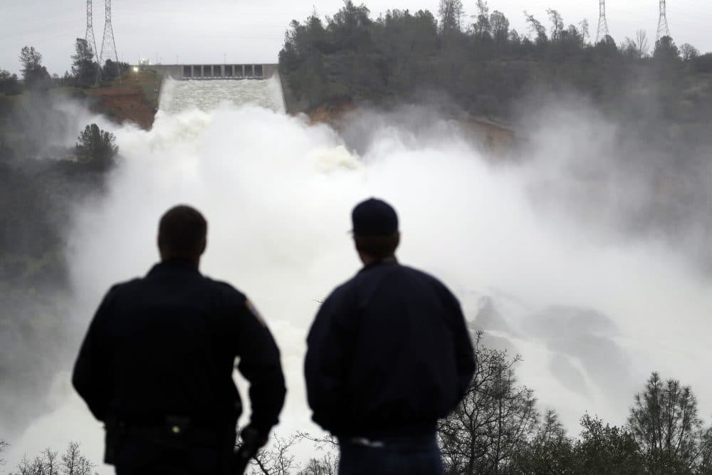 Two men watch as water gushes from the Oroville Dam's main spillway Wednesday, Feb. 15, 2017, in Oroville, Calif. (Marcio Jose Sanchez/AP)