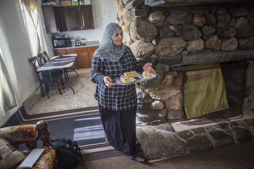 Zenab brings out plates of homemade basbousa, a Syrian coconut cake, for guests to enjoy, (Jesse Costa/WBUR)