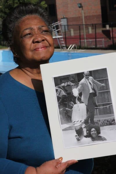 Mimi Jones holds the iconic photo taken of her in the pool in St. Augustine as motel manager James Brock pours acid in. (Courtesy Clennon L. King)