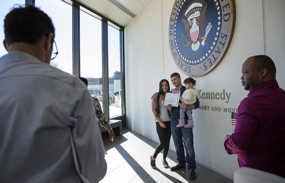Holding his brand new citizenship certificate, Miguel Velez, of Colombia, stops for a photo under the presidential seal at the JFK Library with Katherine Arias, 27, and their 17-month-old daughter. (Robin Lubbock/WBUR)