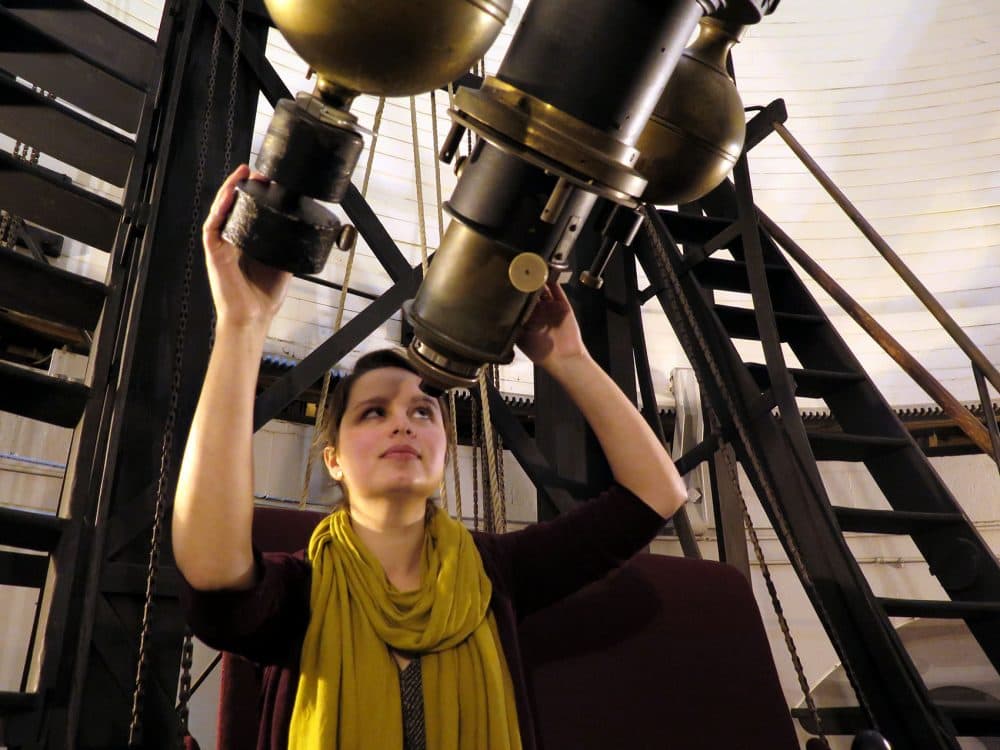 Lindsay Smith, acting curator of the Plate Stacks at the Harvard College Observatory peers through the now-defunct lens of The Great Refractor. (Andrea Shea/WBUR)