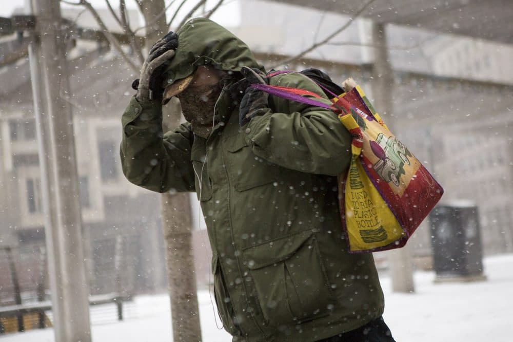 A man hides from the winds whipping through City Hall Plaza. (Jesse Costa/WBUR)