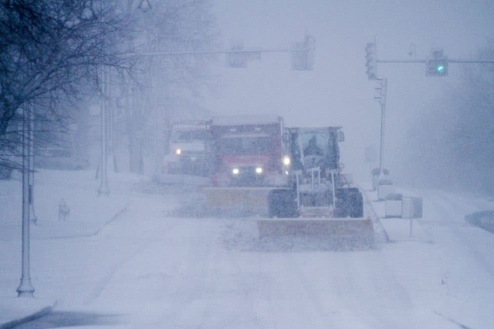 Plows move quickly across a snow-covered roadway. (Jesse Costa/WBUR)