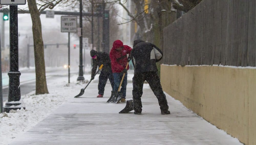 Workers clearing snow from the sidewalk on Binney Street in Kendall Square. (Jesse Costa/WBUR)