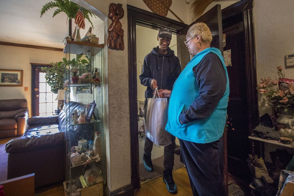 Community Servings delivery coordinator and driver Lee Williams brings a week's worth of food to Kimberly Scarlett at her home in Roxbury. (Jesse Costa/WBUR)